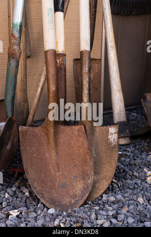 Di lavoro dell'uomo badili appoggiato contro una parete di un capannone. Foto Stock