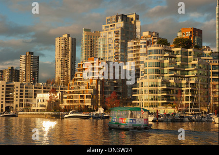 La riflessione di Yaletown edifici appartamento al tramonto attraverso False Creek da Granvile Isola, Vancouver BC Canada Foto Stock