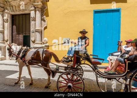 I turisti prendendo un tradizionale Cavallo e Carrozza, Havana, Cuba Foto Stock