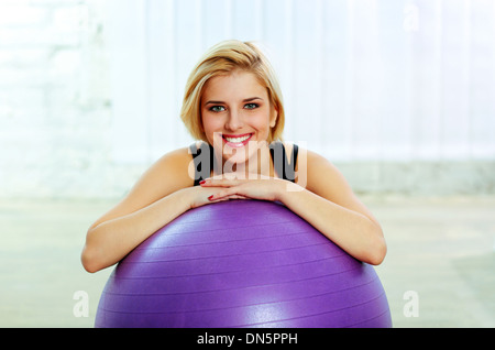 Giovani allegro montare donna appoggiata sul fitball Foto Stock