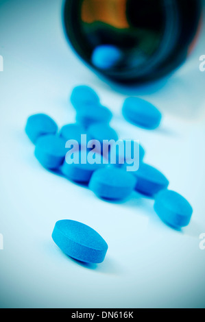 Un mucchio di pillole blu proveniente da una bombola Foto Stock
