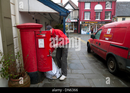 Un lavoratore postale posta di svuotamento in un sacco da un rosso casella postale accanto a un ufficio postale van Llandovery Wales UK KATHY DEWITT Foto Stock