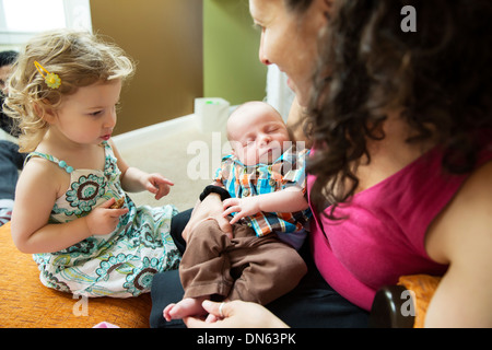 Ragazza caucasica guardando la madre tenere bambino neonato Foto Stock