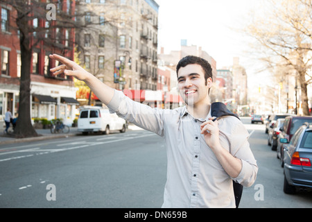 Uomo ispanico salutando taxi sulla strada di città Foto Stock