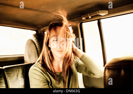 Caucasian donna capelli soffiando in auto Foto Stock