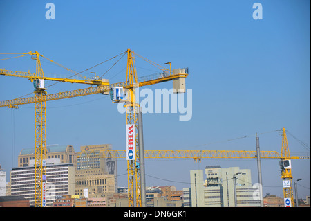 Tre gialli gru a torre al di sopra di una zona urbana. Foto Stock