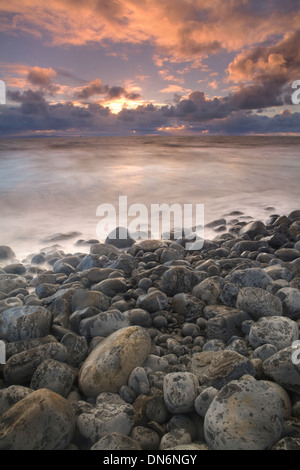 Incredibili nuvole al punto di Nash, Vale of Glamorgan al tramonto come la marea di bobine in schizzi e i ciottoli Foto Stock