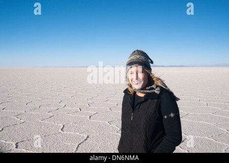 Donna sorridente permanente sulla distesa di sale, Salar de Uyuni, Bolivia, Sud America Foto Stock