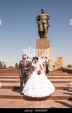 Sposa e lo sposo di fronte della statua di Amir Timur, noto anche come Temur e Tamerlane, Shakhrisabz, Uzbekistan Foto Stock