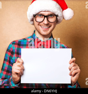 Natale, X-mas, persone, pubblicità, vendita concetto - uomo felice in santa helper hat con vuoto scheda bianca. Hipster stile. Foto Stock