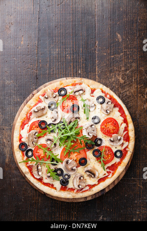 Pizza con funghi e rucola sul tavolo di legno Foto Stock