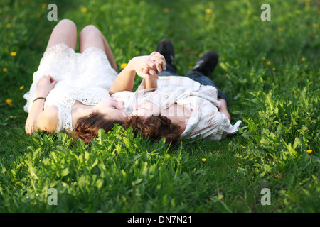 Amare giovane sdraiato su un prato e tenendo le mani Foto Stock