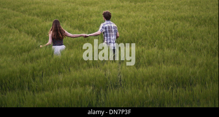 Coppia giovane passeggiate mano nella mano attraverso cornfield Foto Stock