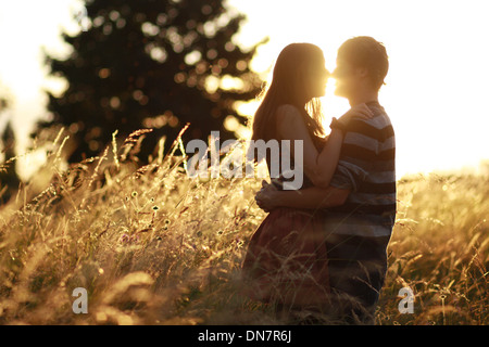 Coppia giovane in amore nel cornfield, kissing in controluce Foto Stock