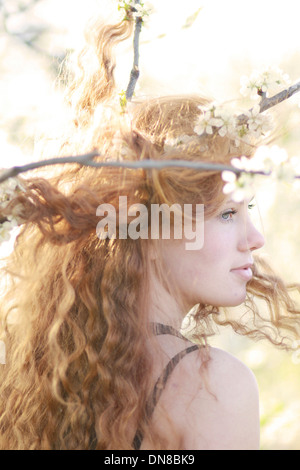 Donna con capelli lunghi tra rami fioriti, ritratto Foto Stock