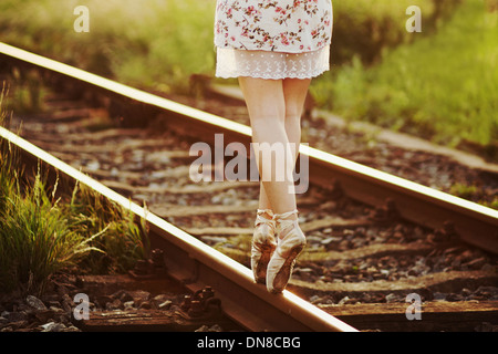 Giovane donna abito in equilibrio su un binario ferroviario Foto Stock