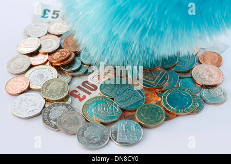 Un piumino spolvero un mucchio di sterling monete e banconote per illustrare pulire il riciclaggio di denaro del concetto. Inghilterra Regno Unito Gran Bretagna Foto Stock