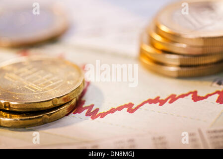 Monete metalliche in euro e un grafico con la curva rossa come un simbolo della fluttuazione dei tassi di cambio. Foto Stock