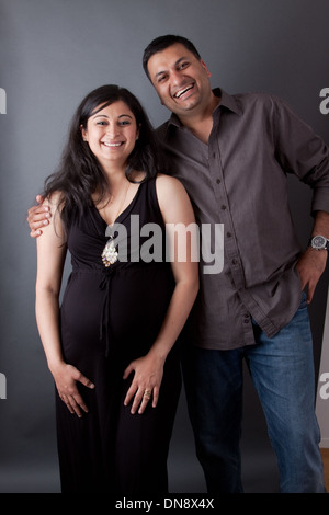 Un East Indian uomo abbraccia la sua moglie incinta che indossa un abito Foto Stock