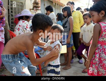 Phnom Penh Cambogia. Undicesimo oct, 2013. Un ragazzo si prende cura del suo fratello più piccolo, che ha ottenuto una libera iniezione antitetanica nella baraccopoli Andong Bei Village in Phnom Penh Cambogia, 11 ottobre 2013. L' UNICEF fornisce vaccini e siringhe per cure mediche. La Cambogia è tra i venti paesi peggiori in cui i bambini soffrono di malnutrizione. Ci sono circa 670.000 orfani. Ogni 22 bambino muore nel primo anno di vita. Foto: Jens Kalaene/dpa/Alamy Live News Foto Stock