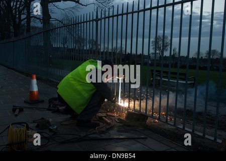 Un consiglio di Lambeth contraente parco riparazioni ringhiere mediante saldatura dei montanti. Foto Stock