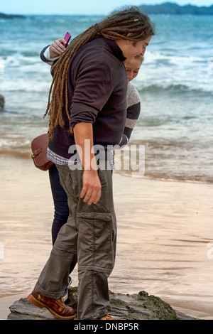 Coppia giovane in equilibrio su una roccia. Harlyn Bay, Cornwall, Inghilterra Foto Stock