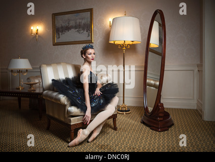 Ballerina in tutù nero seduto in poltrona in interni di lusso Foto Stock