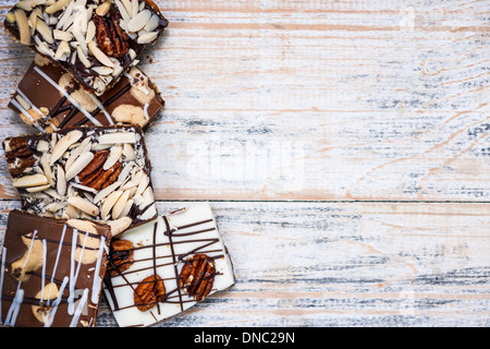 Un assortimento di cioccolato di corteccia di caramello pezzi disposti su sfondo di legno dal di sopra con lo spazio di copia Foto Stock