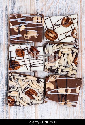 Un assortimento di caramello e cioccolato pezzi di corteccia per dessert disposti su sfondo di legno, vista dall'alto Foto Stock