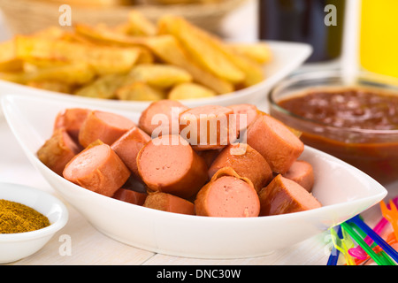 Fritti di pezzi di salsiccia con patatine fritte e curry-ketchup salsa in retro (fuoco selettivo, la messa a fuoco di un terzo in salsicce) Foto Stock