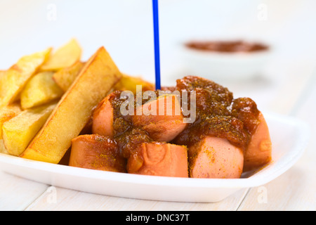 Il tedesco il fast food chiamato Currywurst servito con patate fritte su una piastra monouso in plastica con forcella di partito Foto Stock