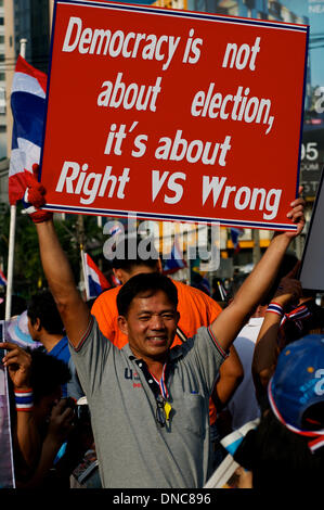 Bangkok, Tailandia. 22 Dic, 2013. Un governo anti-protester detiene un segno sulla democrazia. Decine di migliaia di manifestanti sono scesi in piazza per chiedere le dimissioni del Primo ministro tailandese Yingluck Shinawatra. Credito: Kraig Lieb / Alamy Live News Foto Stock