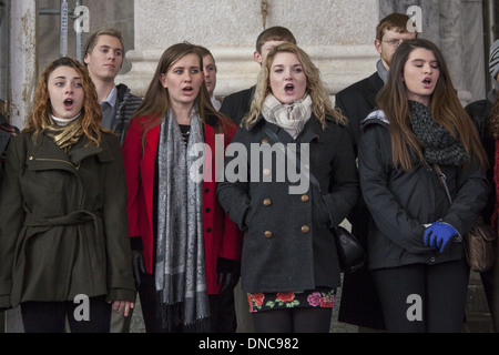 Gruppo di giovani del Natale Carolers sui gradini della cattedrale di San Patrizio cantare per i passanti. Foto Stock