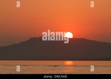 Sole che tramonta dietro la collina sopra il fiume Irrawaddy, Bagan, Myanmar Foto Stock