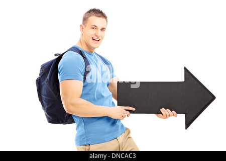 Sorridente giovane con un sacco di scuola tenendo un nero grande freccia rivolta a destra Foto Stock