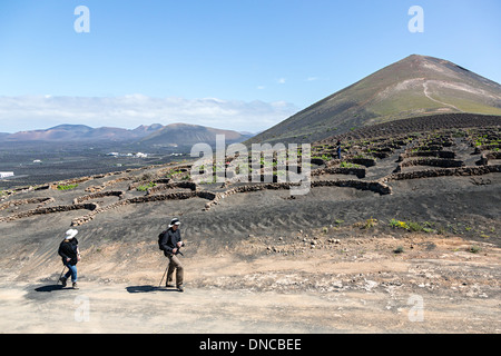 Camminando su una strada sterrata Sentiero attraverso vigneti di La Geria, Lanzarote, Isole Canarie, Spagna Foto Stock