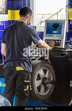 Meccanico nel centro automatico nuovo bilanciamento del pneumatico sulla ruota, Slovenia Foto Stock