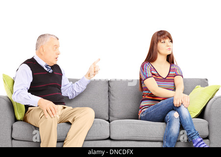 Padre ammonimento di sua figlia disinteressato seduto su un divano Foto Stock
