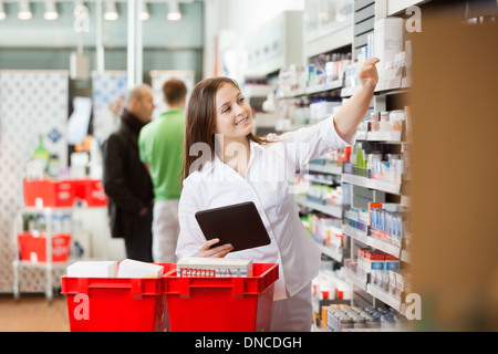 Donna sorridente con tavoletta digitale per lo shopping al supermercato Foto Stock