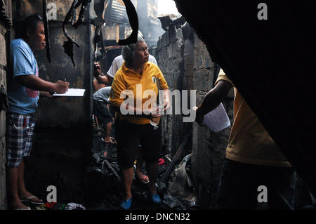 Manila, Filippine. 23 Dic, 2013. I dipendenti governativi tally il numero di case e proprietà bruciato e i nomi dei rispettivi proprietari. Due giorni prima di Natale, un incendio ha colpito una zona residenziale in Barangay aggiunta Hills, suburbana Mandaluyong City, a est di Manila il 23 dicembre 2013. Le relazioni dicono che il fuoco ha iniziato la mattina presto e è stato messo sotto controllo dopo le 9 di mattina.Foto: George Calvelo/NurPhoto Credito: George Calvelo/NurPhoto/ZUMAPRESS.com/Alamy Live News Foto Stock