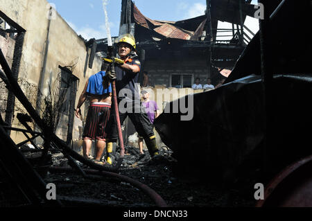 Manila, Filippine. 23 Dic, 2013. Un vigile del fuoco al lavoro in mezzo alle macerie delle case. Due giorni prima di Natale, un incendio ha colpito una zona residenziale in Barangay aggiunta Hills, suburbana Mandaluyong City, a est di Manila il 23 dicembre 2013. Le relazioni dicono che il fuoco ha iniziato la mattina presto e è stato messo sotto controllo dopo le 9 di mattina.Foto: George Calvelo/NurPhoto Credito: George Calvelo/NurPhoto/ZUMAPRESS.com/Alamy Live News Foto Stock