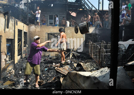 Manila, Filippine. 23 Dic, 2013. I volontari di recupero che cosa è rimasto di proprietà di bruciato. Due giorni prima di Natale, un incendio ha colpito una zona residenziale in Barangay aggiunta Hills, suburbana Mandaluyong City, a est di Manila il 23 dicembre 2013. Le relazioni dicono che il fuoco ha iniziato la mattina presto e è stato messo sotto controllo dopo le 9 di mattina.Foto: George Calvelo/NurPhoto Credito: George Calvelo/NurPhoto/ZUMAPRESS.com/Alamy Live News Foto Stock