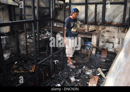 Manila, Filippine. 23 Dic, 2013. Un uomo guarda ciò che rimane della sua casa dopo di correre a casa dal lavoro su di imparare circa il fuoco. Due giorni prima di Natale, un incendio ha colpito una zona residenziale in Barangay aggiunta Hills, suburbana Mandaluyong City, a est di Manila il 23 dicembre 2013. Le relazioni dicono che il fuoco ha iniziato la mattina presto e è stato messo sotto controllo dopo le 9 di mattina.Foto: George Calvelo/NurPhoto Credito: George Calvelo/NurPhoto/ZUMAPRESS.com/Alamy Live News Foto Stock