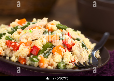 Il cous cous il piatto con il pollo, fagiolo verde, la carota e il peperone rosso servito sulla piastra con la forcella sul lato Foto Stock