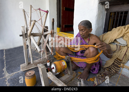 Donna tribale rendendo thread su Charkha, la ruota di filatura, Orissa, India Foto Stock