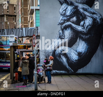 Persone in attesa ad una fermata autobus accanto a un gigante di Fox in Nelson Street Bristol famosa per i suoi ' vedere alcun male ' street art graffiti Foto Stock