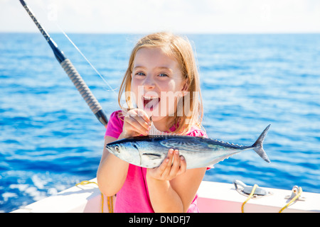 Blonde kid ragazza la pesca del tonno tonni poco felice con trolling fermo sulla coperta della barca Foto Stock