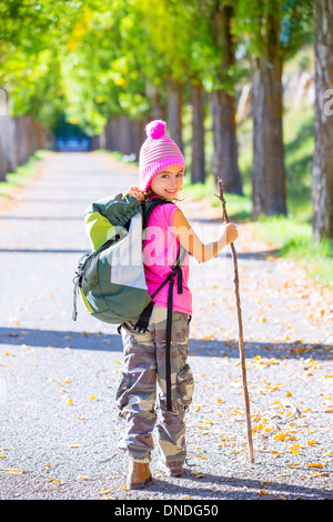 Escursionismo kid ragazza con bastone e zaino esplorare autunno via e Pantalone mimetico Foto Stock