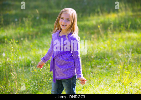 Blonde kid ragazza sorridenti in outdoor verde prato Foto Stock