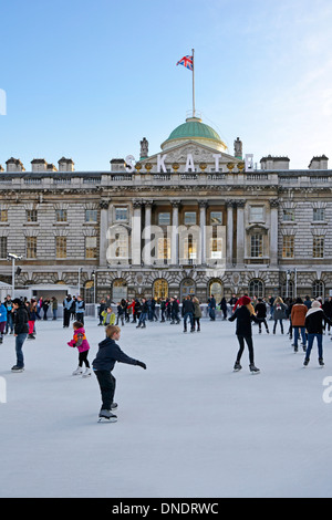 Adulti e bambini pattinatori di ghiaccio con sfondo storico Somerset House Edificio e cortile sulla temporanea pista di pattinaggio invernale Strand Londra Inghilterra Regno Unito Foto Stock